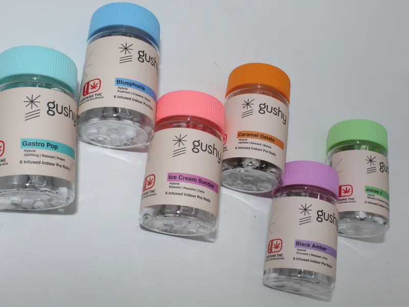 Gushy pre-roll jars scattered across a white table