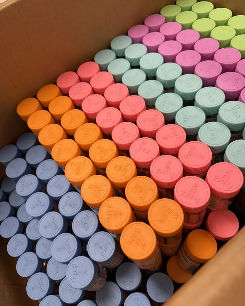 A shipping box packed with hundreds of color-coded Gushy jar lids, ready to be filled