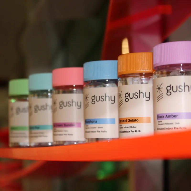 Gushy pre-roll jars lined up on an orange display shelf