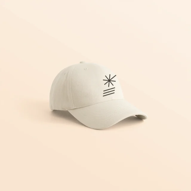 Cream dad hat embroidered with the full Gushy logo, the sun burst over three stripes